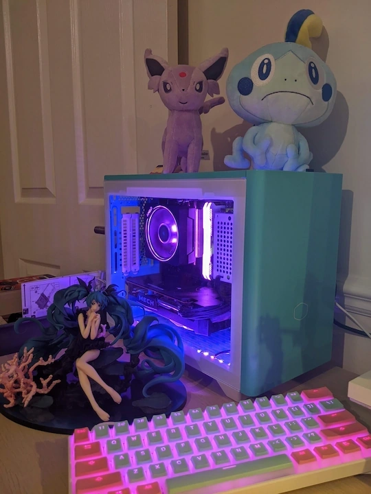 My PC, built with a bright teal case and pink RGB lighting.